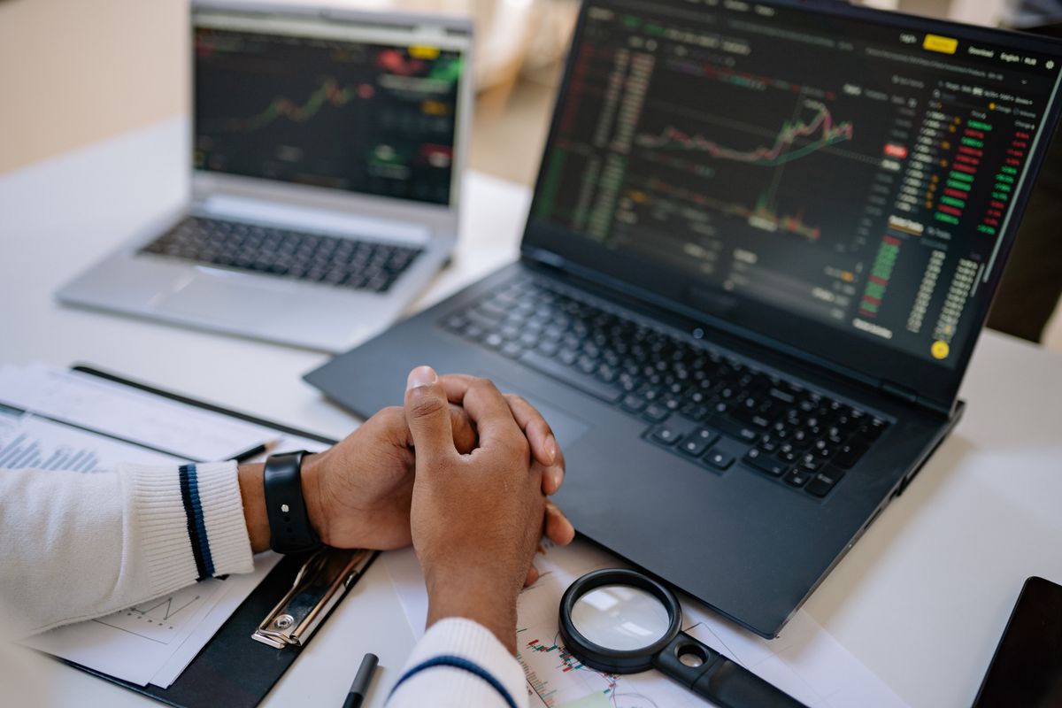 A man at his desk with two laptops, checking markets calmly